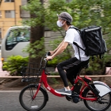 写真：自転車を2人乗りして配達するカップル